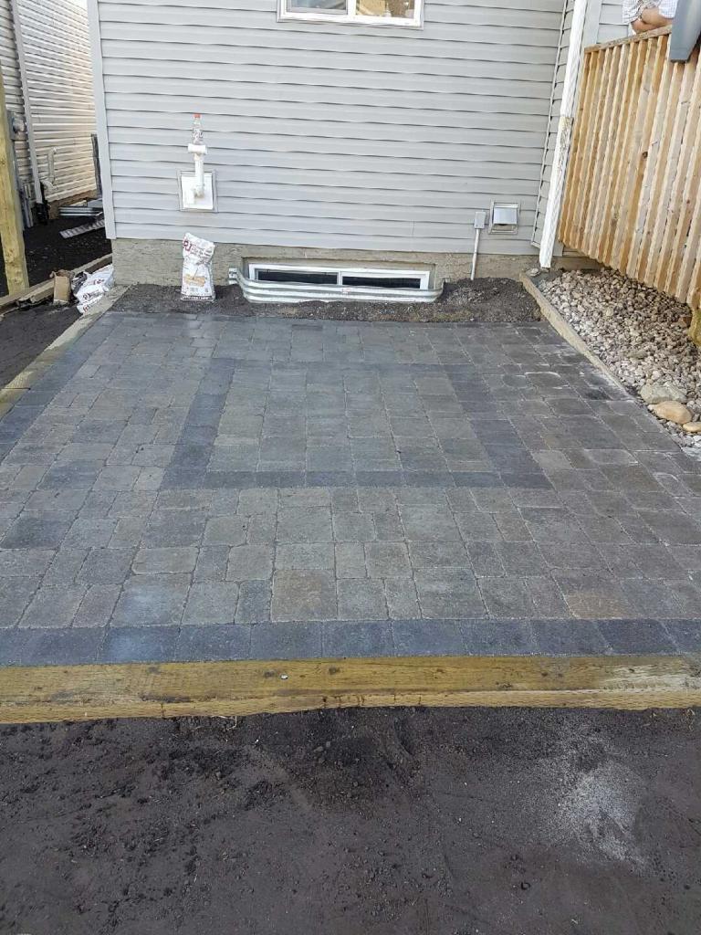 Paver patio with dark contrasting border under construction